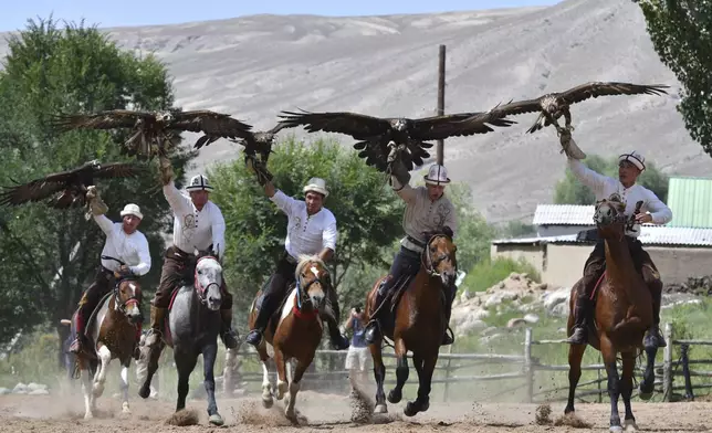 Kyrgyz hunters ride horses with their golden eagles during the Traditional Eagle Hunting Salbuurun Festival on the southern shore of Issyk-Kul lake, 213 km (132 miles) southeast of Bishkek, Kyrgyzstan, on Saturday, Aug. 2, 2025. (AP Photo/Vladimir Voronin)