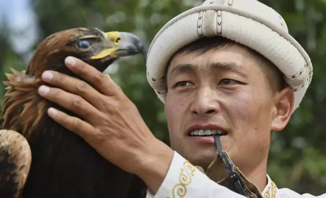 Kyrgyz hunter prepares his golden eagle to take part in competitions in the Traditional Eagle Hunting Salbuurun Festival on the southern shore of Issyk-Kul lake, 213 km (132 miles) southeast of Bishkek, Kyrgyzstan, on Saturday, Aug. 2, 2025. (AP Photo/Vladimir Voronin)