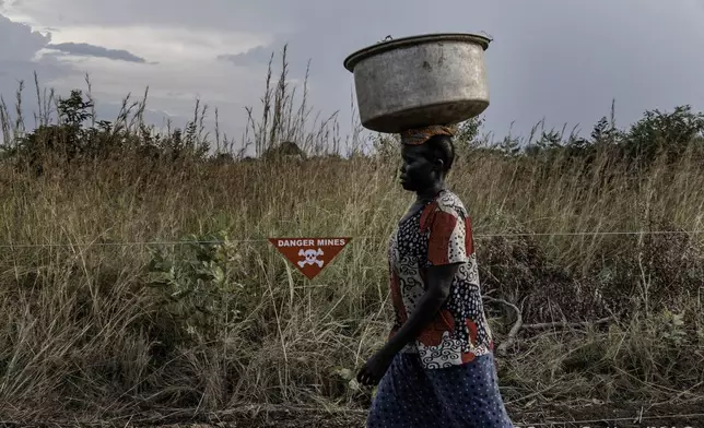 A villager in South Sudan walks past a landmine warning sign. Landmines and explosive remnants of war continue to block safe access to land that could be used for agriculture, schools, housing, infrastructure and water access. Too many families are still living in daily fear. The Mines Advisory Group has worked in South Sudan for over 20 years, helping to save and protect lives through clearing land and raising awareness of the dangers posed by these deadly items.