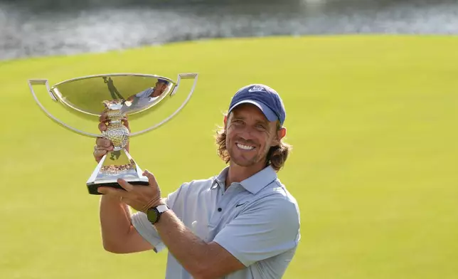 Tommy Fleetwood, of England, holds the championship trophy after the final round of the Tour Championship golf tournament, Sunday, Aug. 24, 2025, in Atlanta. (AP Photo/Mike Stewart)