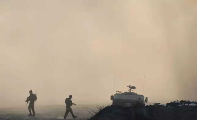 Israeli soldiers walk along the border of the Gaza Strip in southern Israel, Wednesday, Aug. 6, 2025. (AP Photo/Ohad Zwigenberg)