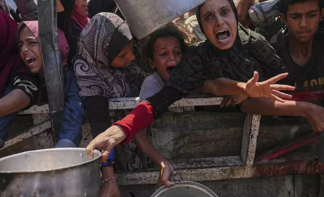 Palestinians struggle to get donated food at a community kitchen in Gaza City, northern Gaza Strip, Monday, Aug. 4, 2025. (AP Photo/Jehad Alshrafi)