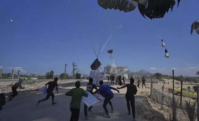 Palestinians rush to collect humanitarian aid airdropped by parachutes into Deir al-Balah, central Gaza Strip, Tuesday, Aug. 5, 2025. (AP Photo/Abdel Kareem Hana)