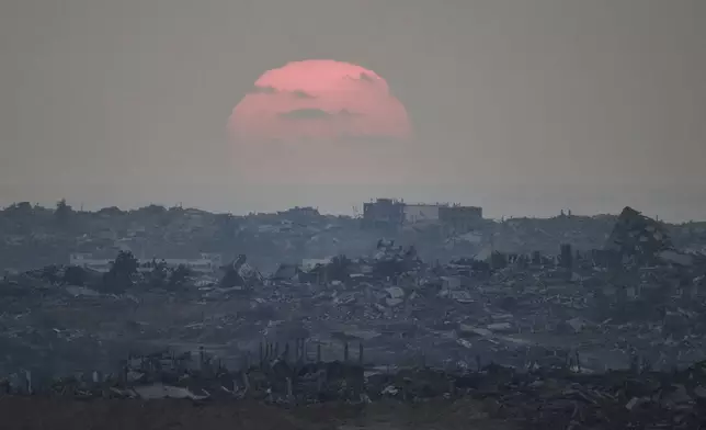The sun sets behind buildings that were destroyed during the Israeli ground and air operations stand in the northern Gaza Strip as seen from southern Israel, Friday, Aug. 8, 2025. (AP Photo/Leo Correa)