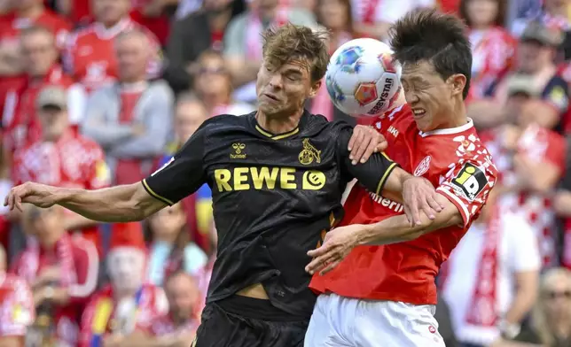 Mainz's Jae-sung Lee, right, plays against Cologne's Joel Schmied during the German Bundesliga soccer match between Mainz and Cologne at the Mewa Arena in Mainz, Germany, Sunday, Aug. 24, 2025. (Torsten Silz/dpa via AP)