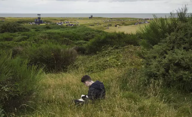 A man reads a book during the second round of the Women's British Open golf championship, at Royal Porthcawl Golf Club in Porthcawl, Wales, Friday, Aug. 1, 2025. (AP Photo/Kin Cheung)