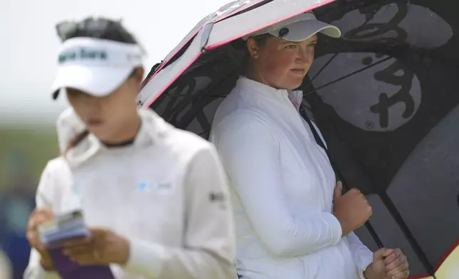 Lydia Ko of New Zealand, left, and Lottie Woad of England wait during the first round of the Women's British Open golf championship, at Royal Porthcawl Golf Club in Porthcawl, Wales, Thursday, July 31, 2025. (AP Photo/Kin Cheung)