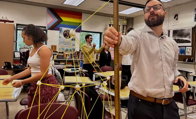Benjamin Franklin High School teacher Chris Dier measures a structure made of pasta and marshmallows created by his students, used as an ice breaker on the second day of classes on Aug. 12, 2025, in New Orleans. (AP Photo/Stephen Smith)