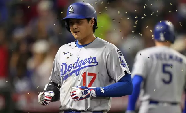 Los Angeles Dodgers' Shohei Ohtani, right, is hit with seeds after hitting a solo home run during the ninth inning of a baseball game against the Los Angeles Angels, Tuesday, Aug. 12, 2025, in Anaheim, Calif. (AP Photo/Mark J. Terrill)