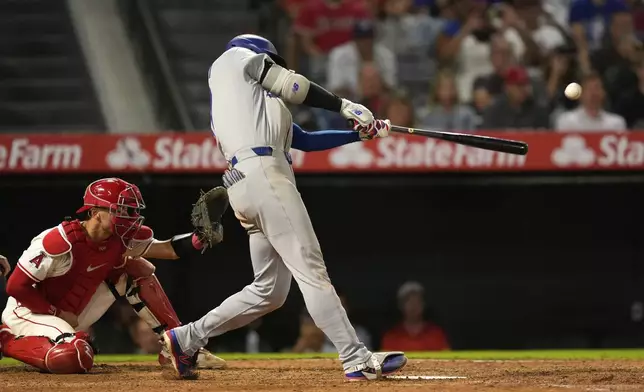 Los Angeles Dodgers' Shohei Ohtani, right, hits a solo home run as Los Angeles Angels catcher Logan O'Hoppe watches during the ninth inning of a baseball game Tuesday, Aug. 12, 2025, in Anaheim, Calif. (AP Photo/Mark J. Terrill)