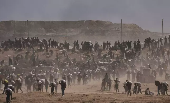 Palestinians carry humanitarian aid packages near a Gaza Humanitarian Foundation distribution center operated by the U.S.-backed organization, in Netzarim, central Gaza Strip, Monday, Aug. 4, 2025. (AP Photo/Abdel Kareem Hana)