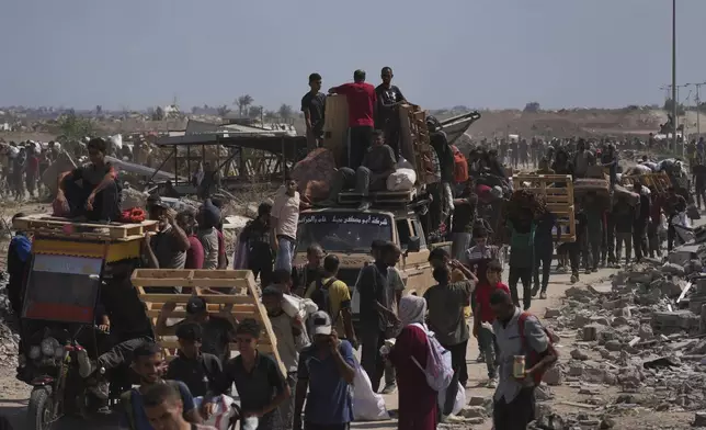 Palestinians carry humanitarian aid packages near a Gaza Humanitarian Foundation distribution center operated by the U.S.-backed organization, in Netzarim, central Gaza Strip, Monday, Aug. 4, 2025. (AP Photo/Abdel Kareem Hana)
