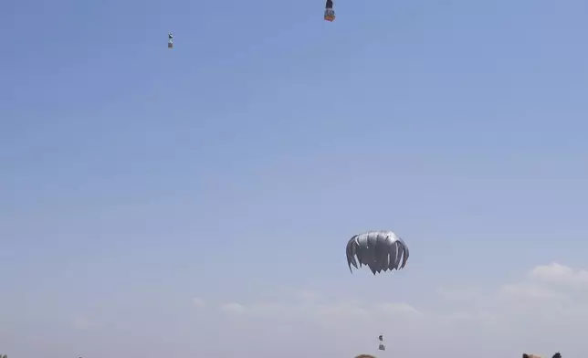Palestinians rush to collect humanitarian aid airdropped by parachutes into Zawaida in the central Gaza Strip, Monday, Aug. 4, 2025. (AP Photo/Abdel Kareem Hana)