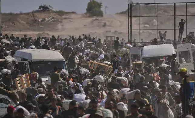 Palestinians carry humanitarian aid packages near a Gaza Humanitarian Foundation distribution center operated by the U.S.-backed organization, in Netzarim, central Gaza Strip, Monday, Aug. 4, 2025. (AP Photo/Abdel Kareem Hana)