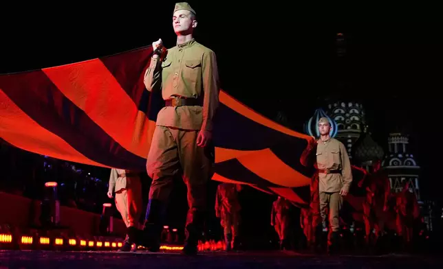 Russian servicemen carry a giant St. George ribbon, a symbol of Soviet participation in World War II, during a dress rehearsal of the Spasskaya Tower International Military Music Festival on the Red square in Moscow, Thursday, Aug. 21, 2025. (AP Photo/Pavel Bednyakov)