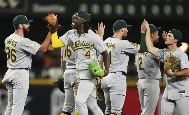 Athletics center fielder Lawrence Butler (4) greets pitcher Hogan Harris (36) as they celebrate a win over the Seattle Mariners in 10 innings of a baseball game Saturday, Aug. 23, 2025, in Seattle. (AP Photo/Lindsey Wasson)