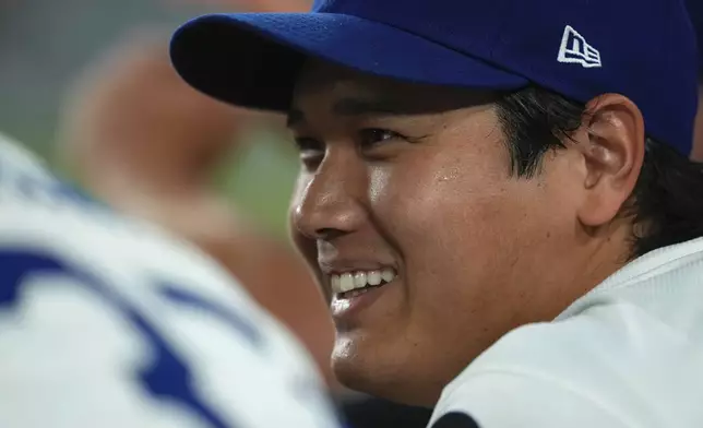 Los Angeles Dodgers' Shohei Ohtani chats with Teoscar Hernández in the dugout during the ninth inning of a baseball game against the San Diego Padres, Friday, Aug. 15, 2025, in Los Angeles. (AP Photo/Mark J. Terrill)