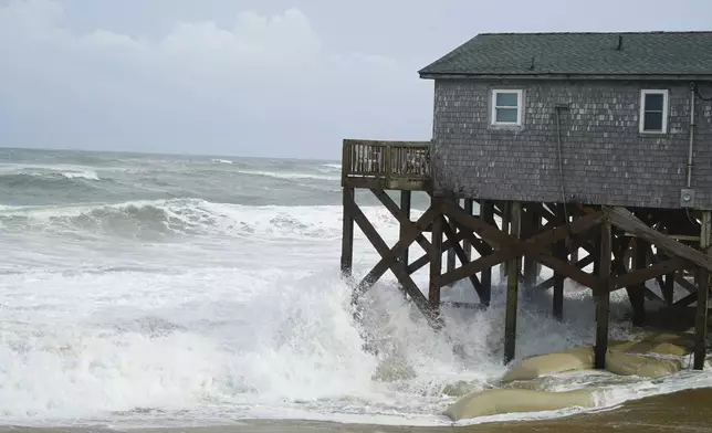 Waves from Hurricane Erin crash against the sandbagged pilings of a building in Buxton, N.C., on Wednesday, Aug. 20, 2025. (AP Photo/Allen G. Breed)