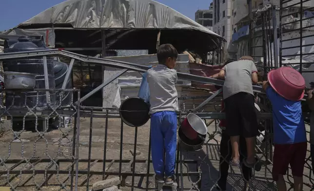 A Palestinian children wait at a community kitchen before donated food is prepared and distributed in Gaza City, Friday, Aug. 22, 2025. (AP Photo/Abdel Kareem Hana)