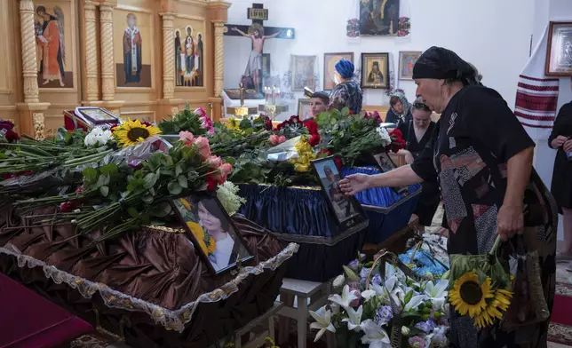 CAPTION CORRECTS THE SPELLING - Mourners at the funeral of Natalia Haiova, her sons Vladyslav and Roman, and her brother Oleksandr, who were killed in their apartment in Kyiv during the Russian strike on July 31, in Ivankovychi, Kyiv region, Ukraine, Tuesday, Aug. 5, 2025. (AP Photo/Danylo Antoniuk)