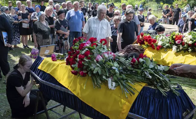CAPTION CORRECTS THE SPELLING - Mourners at the funeral of Natalia Haiova, her sons Vladyslav and Roman, and her brother Oleksandr, who were killed in their apartment in Kyiv during the Russian strike on July 31, in Ivankovychi, Kyiv region, Ukraine, Tuesday, Aug. 5, 2025. (AP Photo/Danylo Antoniuk)