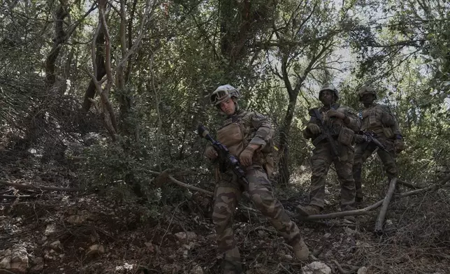 French U.N. peacekeepers walk through bushes as they search for Hezbollah weapons in the Saluki Valley, south Lebanon, Wednesday, Aug. 20, 2025. (AP Photo/Hussein Malla)
