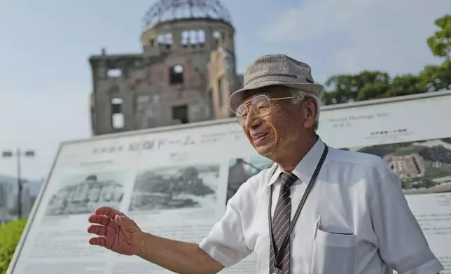 Kunihio Iida, atomic bomb survivor and a volunteer guide the iconic exhibition hall best known as the Atomic Bomb Dome speaks in English to foreign visitors on Wednesday, July 9, 2025, in Hiroshima, western Japan. (AP Photo/Eugene Hoshiko)