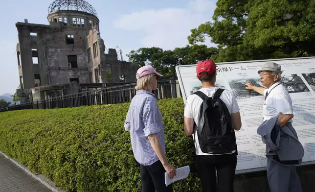 Kunihio Iida, atomic bomb survivor and a volunteer guide the iconic exhibition hall best known as the Atomic Bomb Dome speaks in English to foreign visitors on Wednesday, July 9, 2025, in Hiroshima, western Japan. (AP Photo/Eugene Hoshiko)