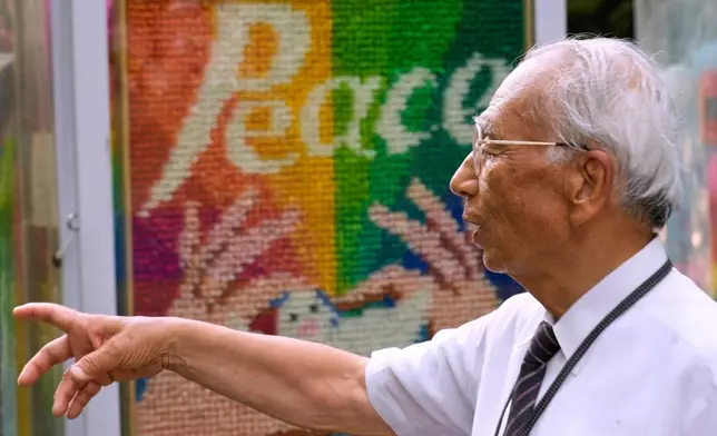 Kunihio Iida, atomic bomb survivor and a volunteer guide speaks in English to foreign visitors at the Children's Peace Monument where the place where people offer paper cranes to honor the victims of the 1945 atomic bomb on Wednesday, July 9, 2025, in Hiroshima, western Japan. (AP Photo/Eugene Hoshiko)