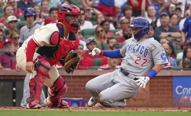 Chicago Cubs' Seiya Suzuki (27) scores past St. Louis Cardinals catcher Yohel Pozo during the second inning of a baseball game Saturday, Aug. 9, 2025, in St. Louis. (AP Photo/Jeff Roberson)