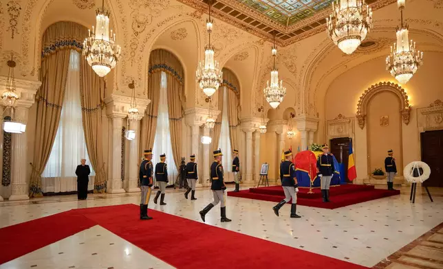 Honor guard soldiers perform a changing of the guard by the coffin of late Ion Iliescu, Romania's first freely elected president after the fall of communism in 1989, at the Cotroceni Presidential Palace, in Bucharest, Romania, Wednesday, Aug. 6, 2025.(AP Photo/Vadim Ghirda)