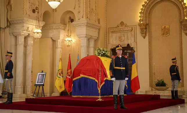 Honor guard soldiers stand next to the coffin of the late Ion Iliescu, Romania's first freely elected president after the fall of communism in 1989, at the Cotroceni Presidential Palace, in Bucharest, Romania, Wednesday, Aug. 6, 2025.(AP Photo/Vadim Ghirda)
