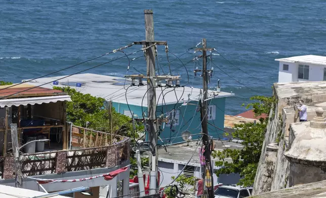 Power lines and utility poles stand in front of La Perla neighborhood along the coast in Old San Juan, Puerto Rico, as Hurricane Erin approaches, Friday, Aug. 15, 2025. (AP Photo/Alejandro Granadillo)