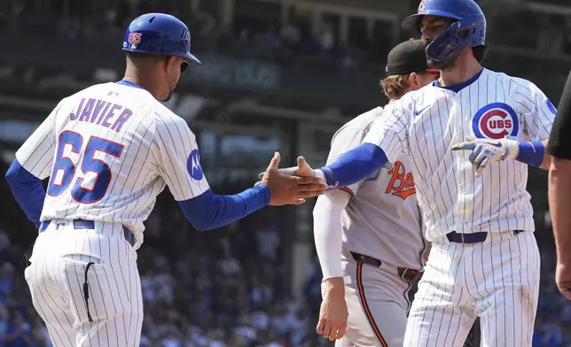 Chicago Cubs' Dansby Swanson, front right, celebrates with first base coach Jose Javier (65) after hitting a one-run single during the sixth inning of a baseball game against the Baltimore Orioles in Chicago, Sunday, Aug. 3, 2025. (AP Photo/Nam Y. Huh)
