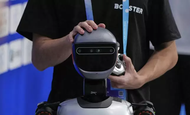 A technician examines the head of a robot at the World Humanoid Robot Games Beijing, China, Saturday, Aug. 16, 2025. (AP Photo/Mahesh Kumar A.)