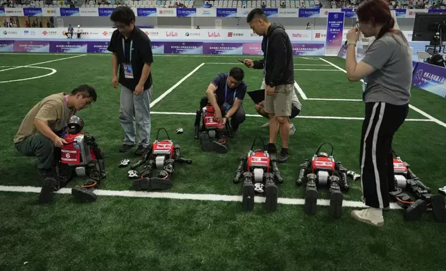 Technicians work on robots before a soccer game at the World Humanoid Robot Games held in Beijing, China, Friday, Aug. 15, 2025. (AP Photo/Mahesh Kumar A.)