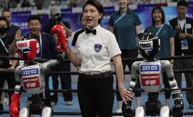 A referee announces the winner of a Free Combat event during the World Humanoid Robot Games held in Beijing, China, Saturday, Aug. 16, 2025. (AP Photo/Mahesh Kumar A.)