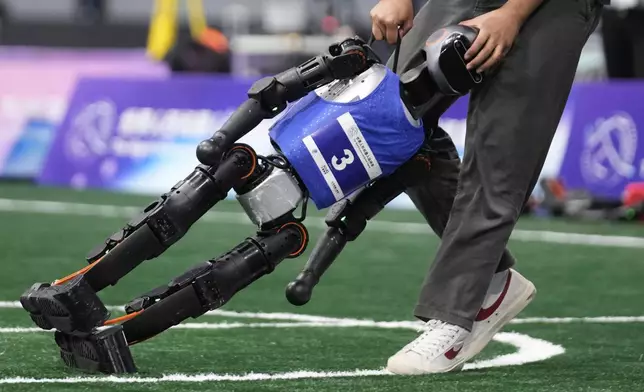 A technician assists a robot during a Soccer Event at the World Humanoid Robot Games in Beijing, China, Friday, Aug. 15, 2025. (AP Photo/Mahesh Kumar A.)