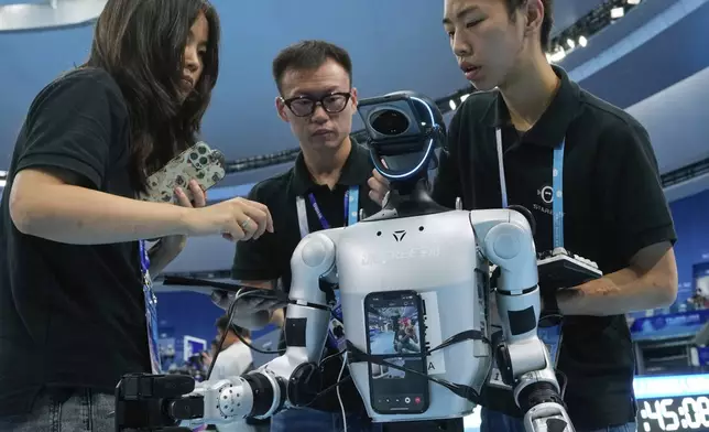 Technicians check a robot after it fell during an event during the World Humanoid Robot Games held in Beijing, China, Saturday, Aug. 16, 2025. (AP Photo/Mahesh Kumar A.)