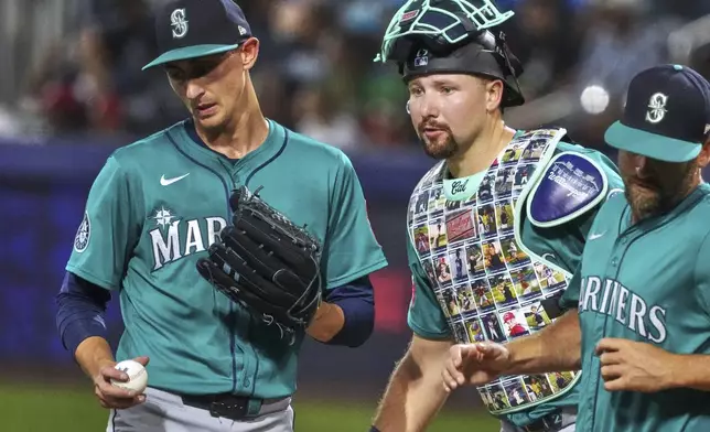 Seattle Mariners pitcher George Kirby, left, gets a visit from catcher Cal Raleigh, center, and pitching coach Pete Woodworth during the second inning of the Little League Classic baseball game at Bowman Field in Williamsport, Pa., Sunday, Aug. 17, 2025. (AP Photo/Gene J. Puskar)