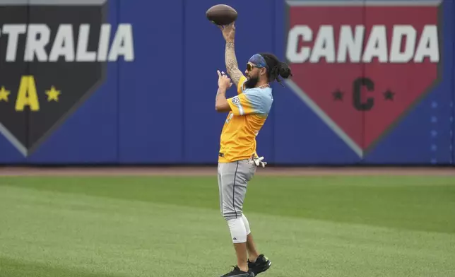 Seattle Mariners' J.P. Crawford tosses a football in the outfield before the Little League Classic baseball game against the New York Mets at Bowman Field in Williamsport, Pa., Sunday, Aug. 17, 2025. (AP Photo/Gene J. Puskar)