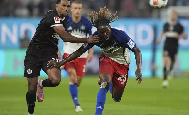 FC St. Pauli's Andreas Hountondji, left, and Hamburger SV's Jordan Torunarigha chase after for the ball during the German Bundesliga soccer match between Hamburger SV and FC St. Pauli at Volksparkstadion in Hamburg, Germany, Friday, Aug. 29, 2025. (Marcus Brandt/dpa via AP)