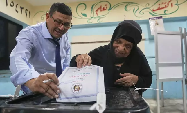An elderly voter is helped as she casts her vote at a polling station during the first day of the Senate election in Cairo, Egypt, Monday, Aug. 4, 2025. (AP Photo/Amr Nabil)