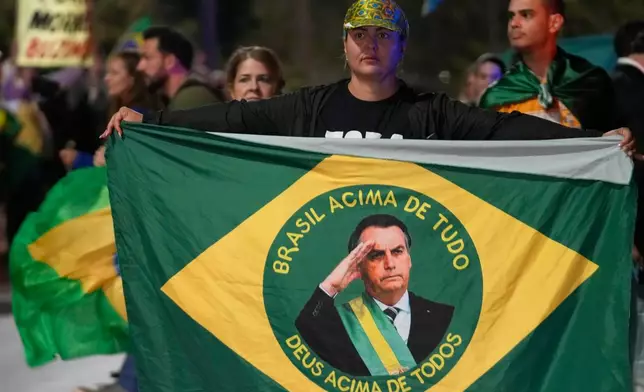 Demonstrators rally in support of former President Jair Bolsonaro at the entrance to his residential complex, to denounce his house arrest order by the Supreme Court, in Brasília, Brazil, Tuesday, Aug. 5, 2025. (AP Photo/Eraldo Peres)