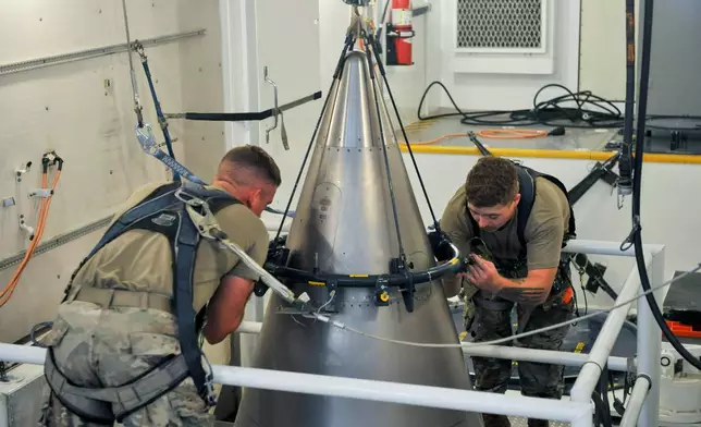 FILE - In this image provided by the U.S. Air Force, Senior Airman Jacob Deas and Airman 1st Class Jonathan Marrs secure a titanium shroud, beneath which is a nuclear warhead, at the top of a Minuteman III intercontinental ballistic missile, Aug. 24, 2023, at the Malmstrom Air Force Base in Great Falls, Mont. (John Turner/U.S. Air Force via AP, File)
