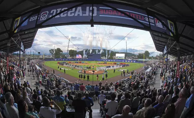 The 20 Little League teams participating in the Little League World Series line the infield as the Seattle Mariners, line the third baseline, and the New York Mets line the first baseline before the Little League Classic baseball game at Bowman Field in Williamsport, Pa., Sunday, Aug. 17, 2025. (AP Photo/Gene J. Puskar)