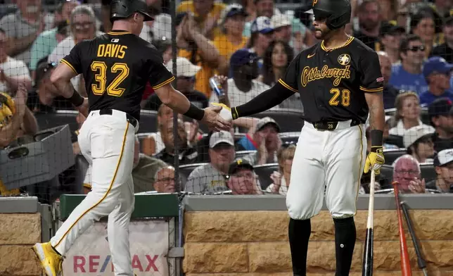Pittsburgh Pirates' Henry Davis, left, is greeted by Tommy Pham, right, after scoring on a wild pitch during the seventh inning of a baseball game against the Toronto Blue Jays, Monday, Aug. 18, 2025, in Pittsburgh. (AP Photo/Matt Freed)