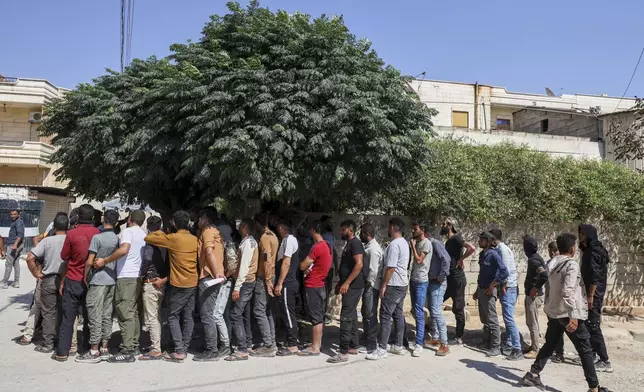 Young Kurdish men line up to sign up to join the Syrian government's General Security forces at a police station in Afrin, Syria, an area in the country's north from which Kurds were forcibly displaced years ago, Thursday Aug. 21, 2025. (AP Photo/Omar Albam)