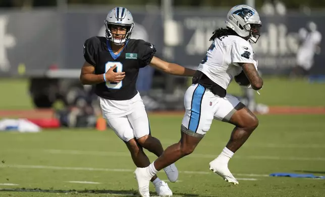 Carolina Panthers quarterback Bryce Young (9) hands off to running back Rico Dowdle during a joint NFL football practice with the Houston Texans Thursday, Aug. 14, 2025, in Houston. (AP Photo/Ashley Landis)