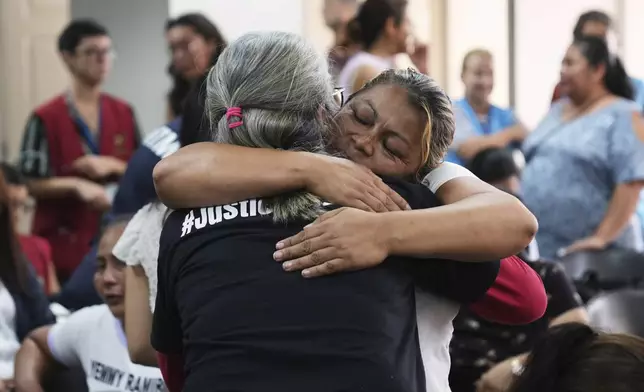 Relatives of the 41 girls killed in a fire at a government-run facility for at-risk girls in 2017, embrace in a courtroom during a hearing for seven people accused of responsibility, in Guatemala City, Tuesday, Aug. 12, 2025. (AP Photo/Moises Castillo)